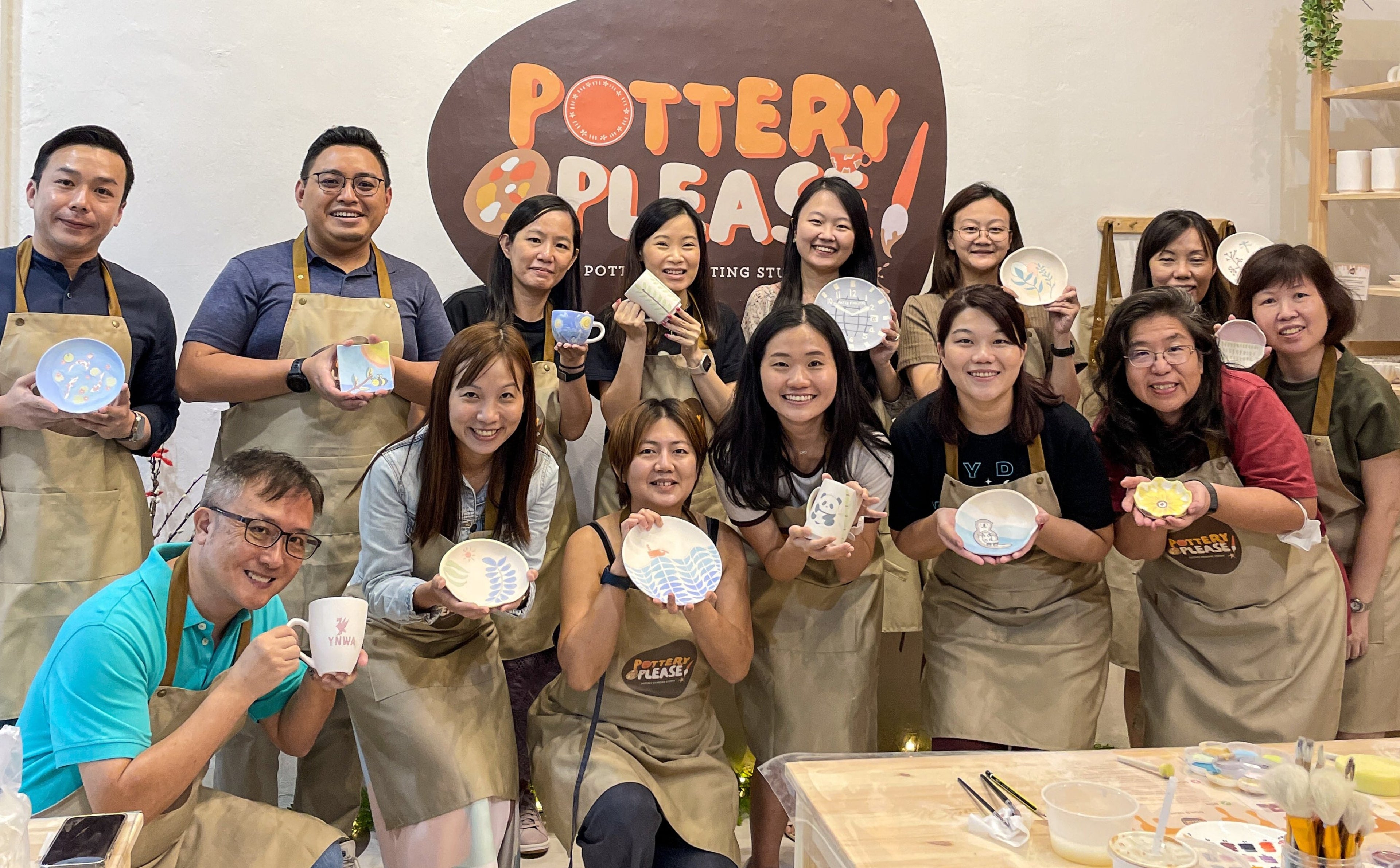 Team bonding during a corporate pottery painting event at PotteryPlease! in Singapore.