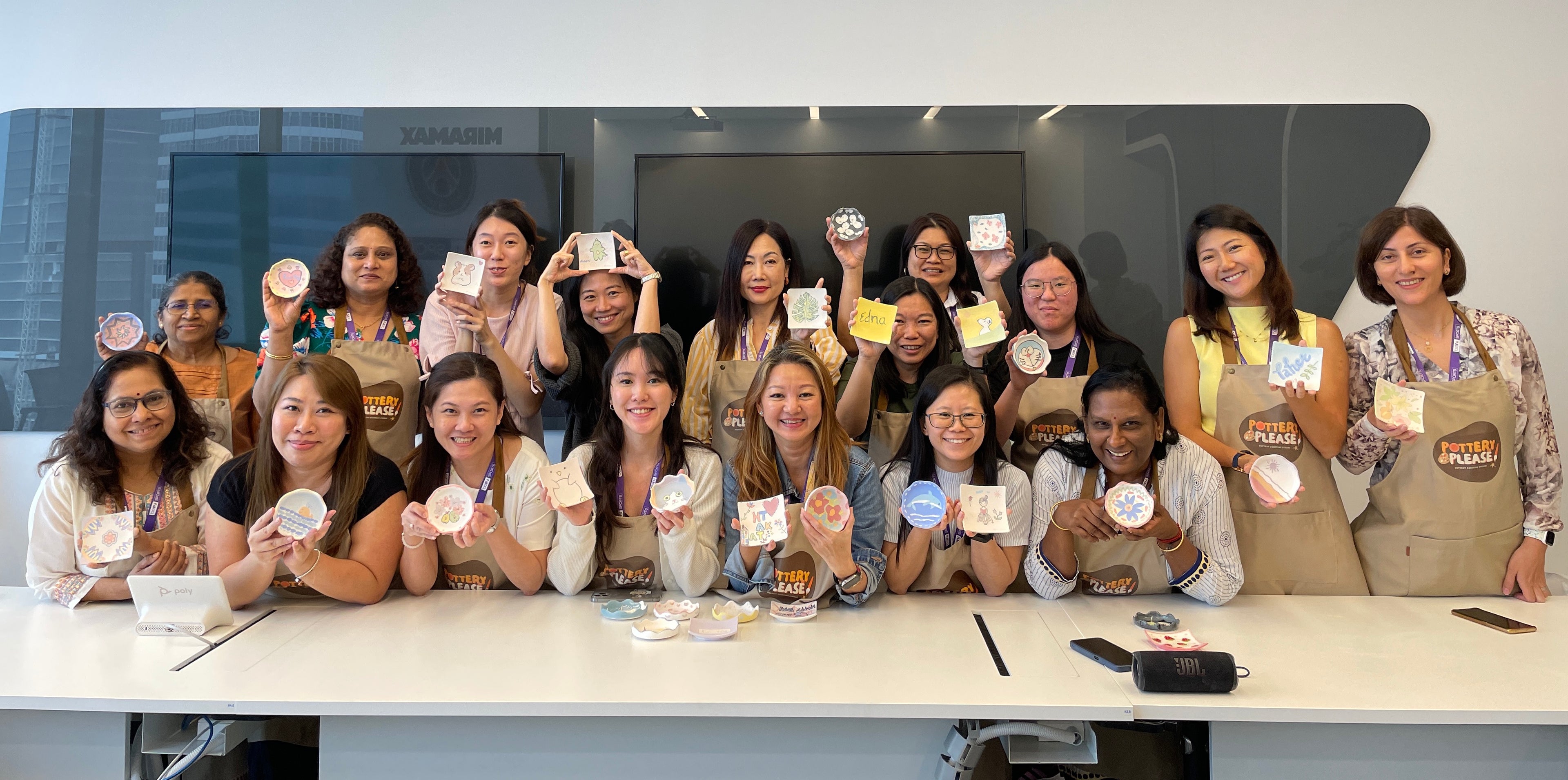 Customers smiling with their finished pottery pieces for a group photo, PotteryPlease offering an external pottery painting event at a client’s venue.