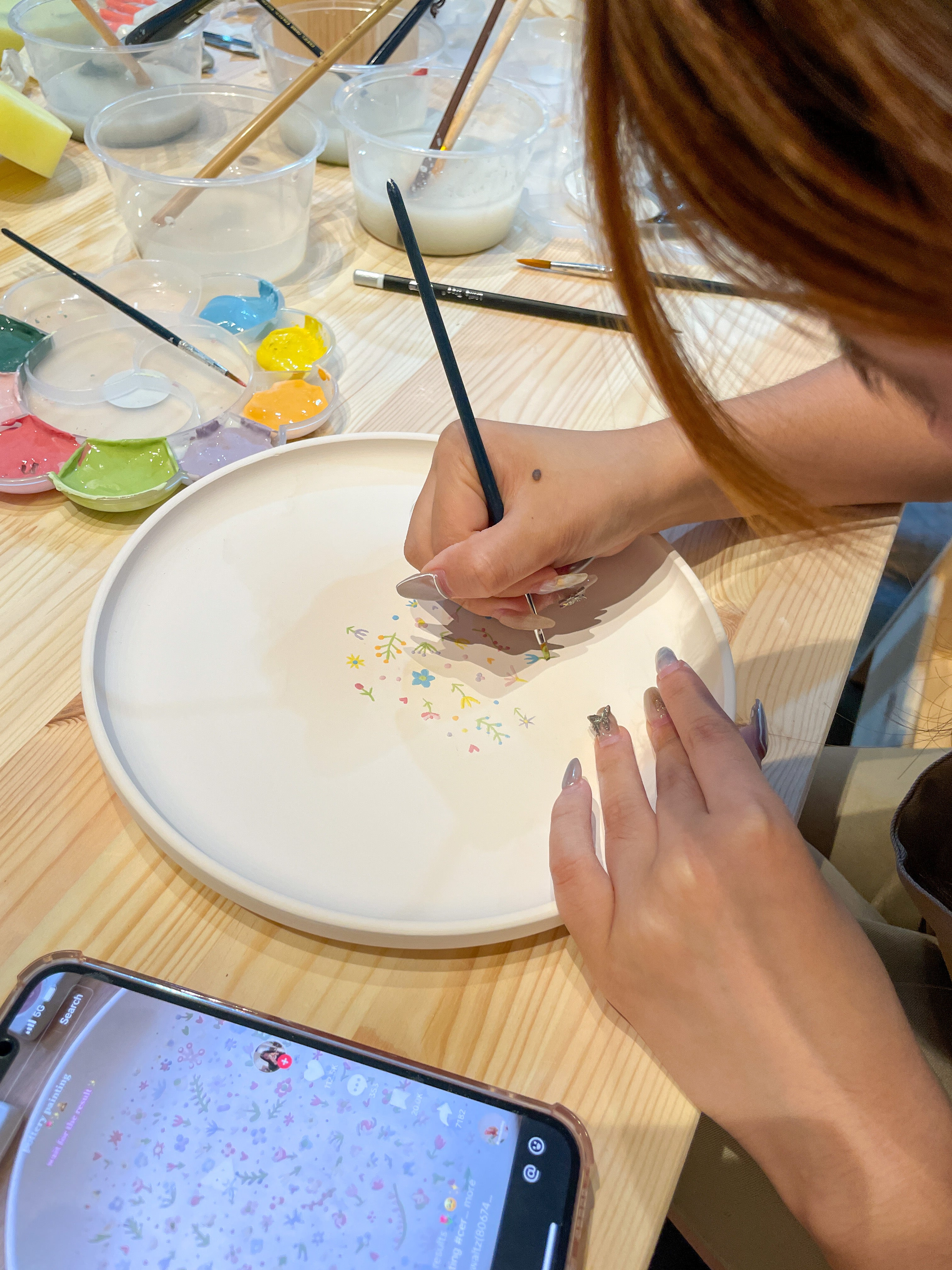 Customer painting a pottery piece with vibrant colors at PotteryPlease! Singapore